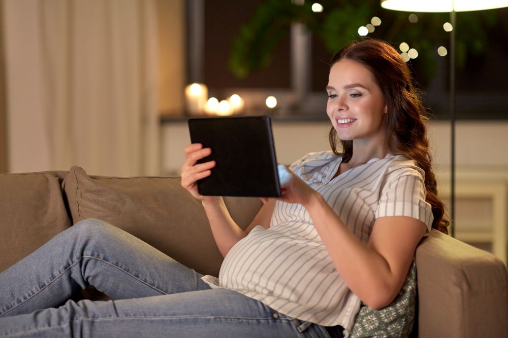pregnancy, technology and people concept - happy pregnant woman with tablet pc computer at home. happy pregnant woman with tablet pc at home