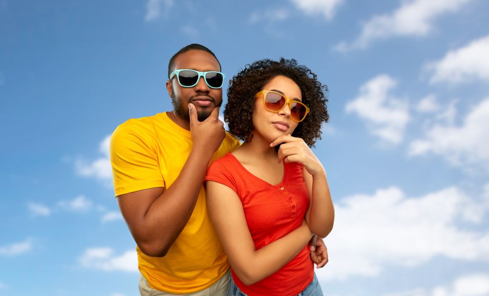 people, accessories and summer concept - african american couple in sunglasses thinking over grey background. african couple in sunglasses thinking