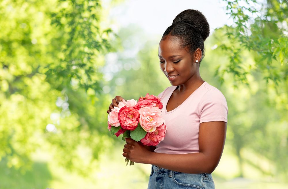 people and international women&rsquo;s day concept - happy african american young woman with bunch of peony flowers over green natural background. happy african american woman with bunch of flowers