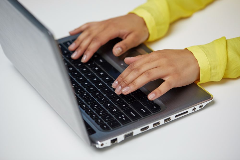 education, technology and people concept - close up of hands of african american woman typing on laptop computer. african american student girl typing on laptop