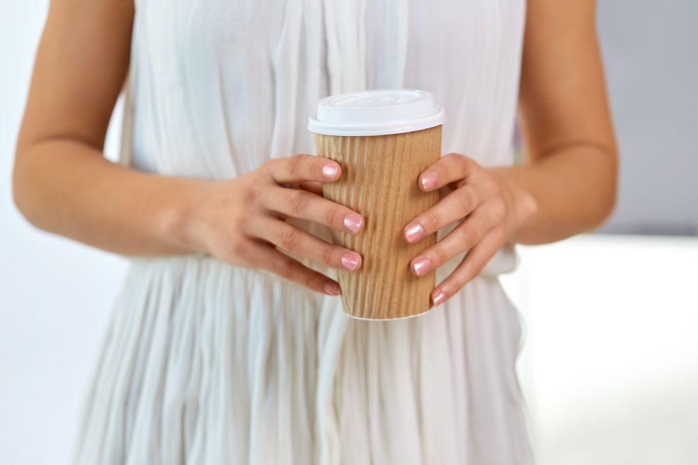 drinks and people concept - close up of woman holding takeaway coffee cup. close up of woman holding takeaway coffee cup