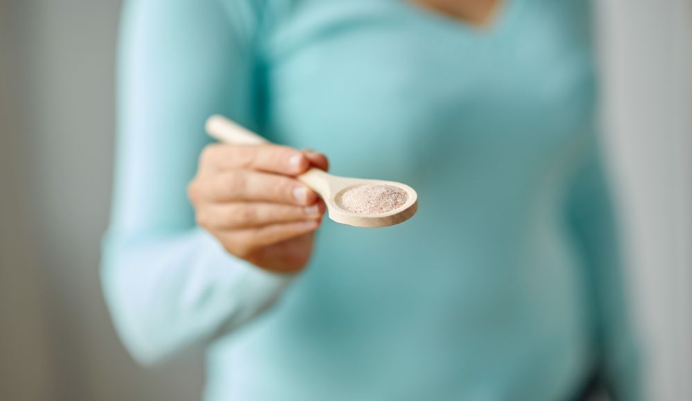 food cooking, culinary and eating concept - close up of woman with sea salt on wooden spoon. close up of woman with sea salt on wooden spoon