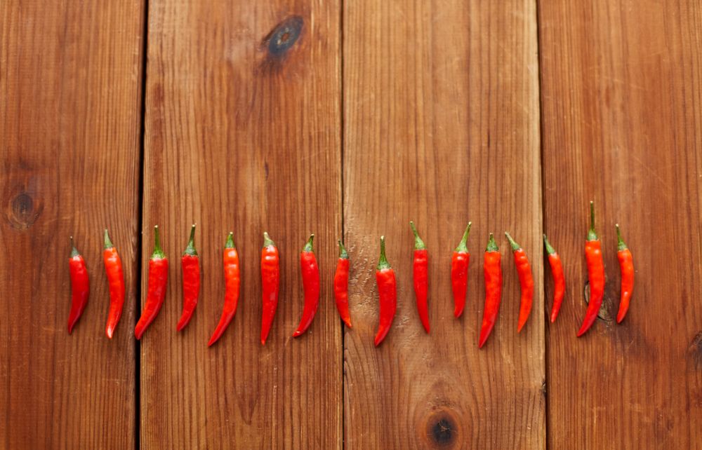 cooking, food and culinary concept - red chili or cayenne pepper on wooden boards. red chili or cayenne pepper on wooden boards