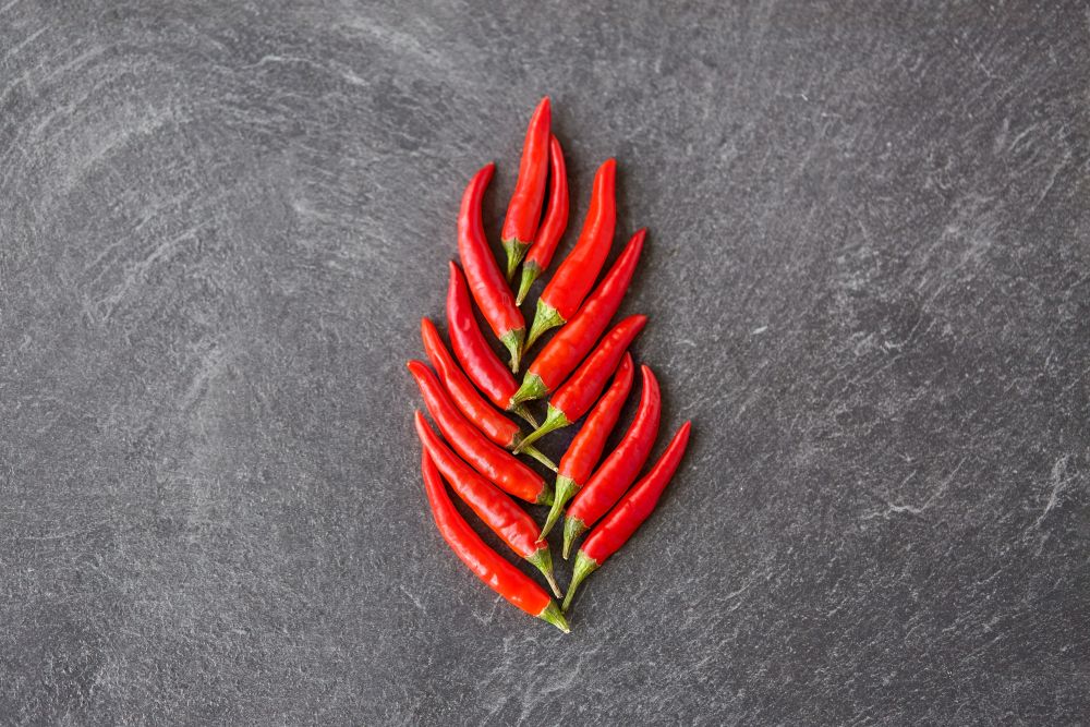 cooking, food and culinary concept - red chili or cayenne pepper on slate stone surface. red chili or cayenne pepper on slate stone surface