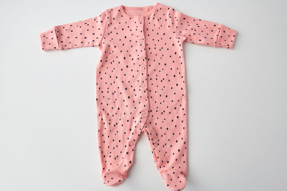 clothes, babyhood and clothing concept - pink long-sleeved bodysuit for baby girl with dot print on white background. pink bodysuit for baby girl on white background