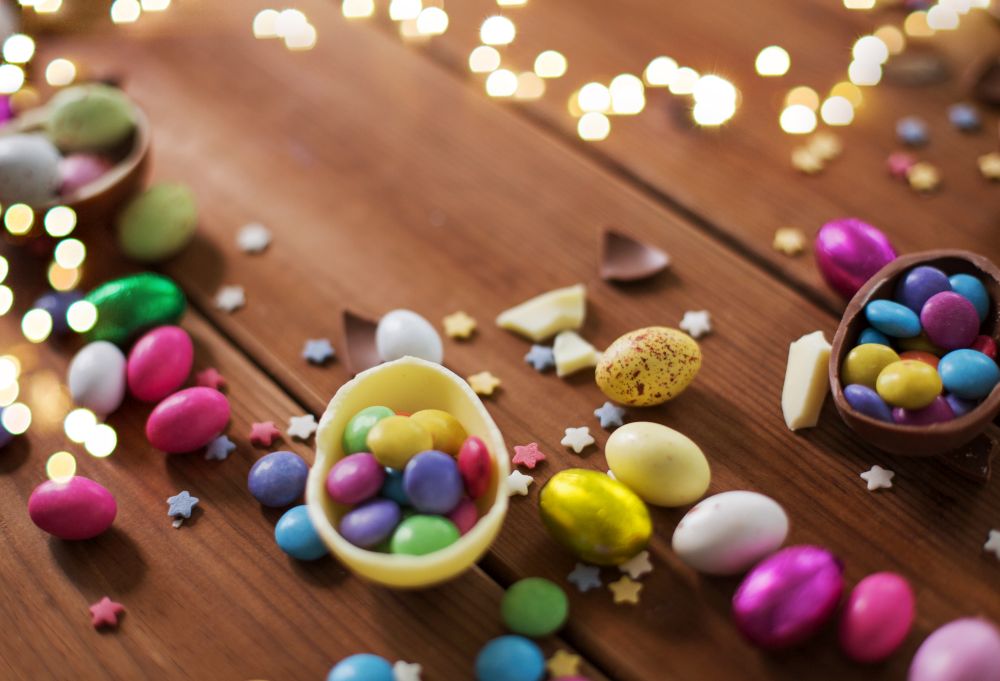 easter, sweets and confectionery concept - close up of chocolate eggs and candy drops on wooden background. chocolate eggs and candy drops on wooden table