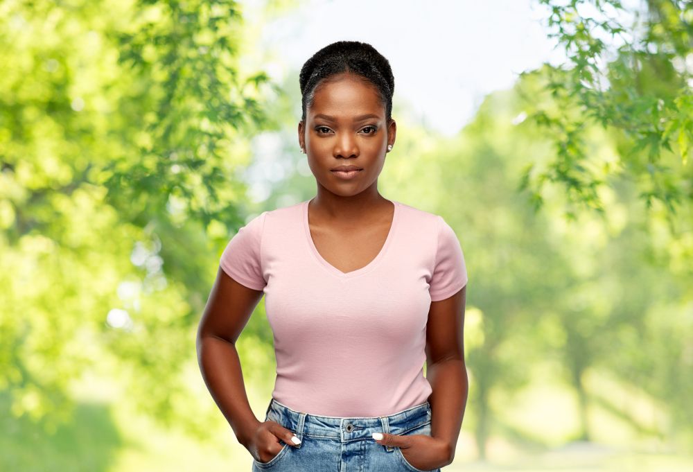 people, ethnicity and portrait concept - african american young woman over green natural background. african american woman over natural background