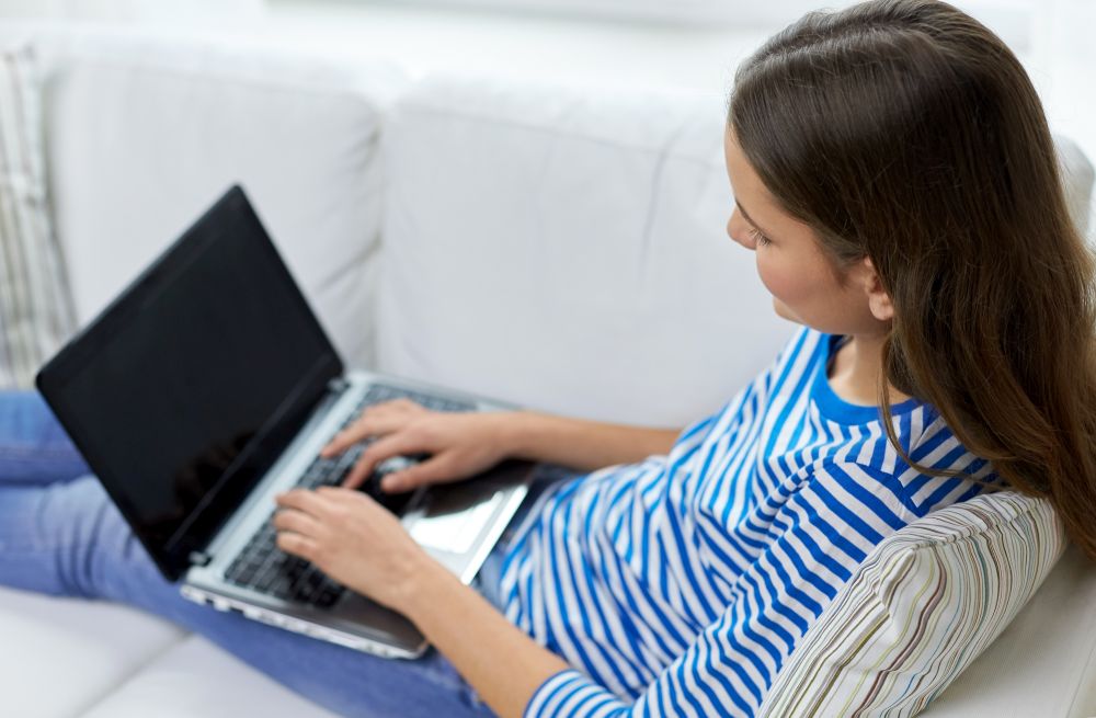 technology and people concept - close up of teenage girl typing on laptop at home. close up of teenage girl typing on laptop at home