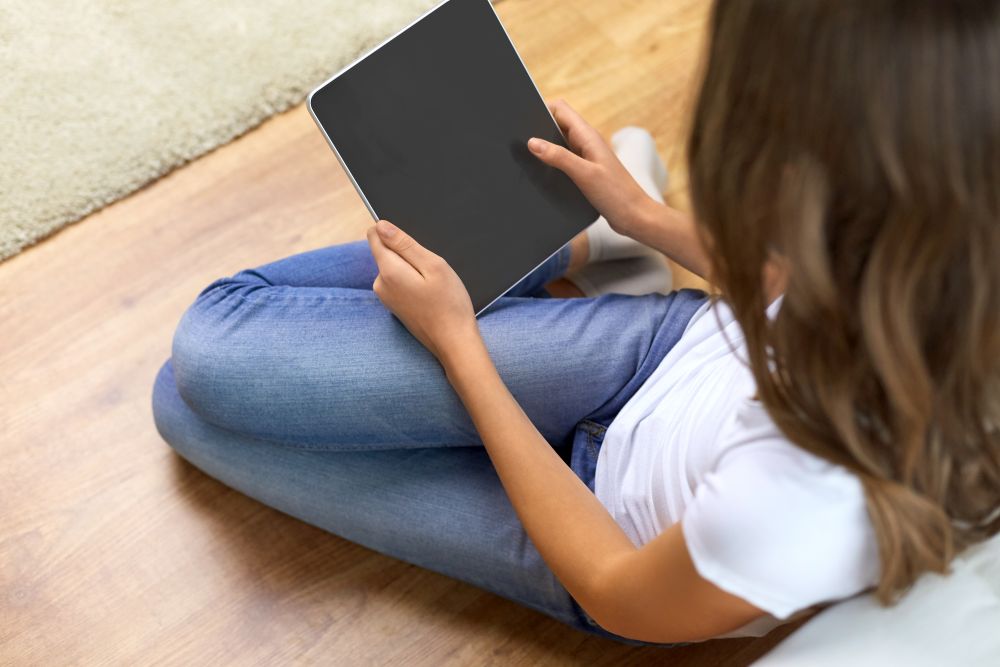 technology and people concept - close up of teenage girl with tablet pc computer sitting on floor at home. teenage girl with tablet pc computer at home