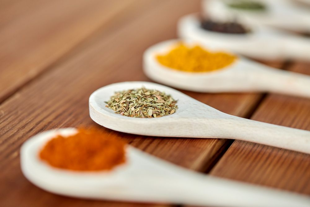food, culinary and unhealthy eating concept - spoons with different spices on wooden table. spoons with different spices on wooden table