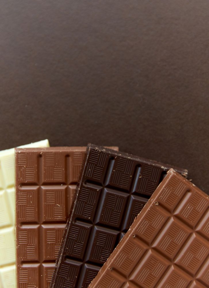 sweets, confectionery and food concept - milk, dark and white chocolate bars on brown background. different kinds of chocolate on brown background