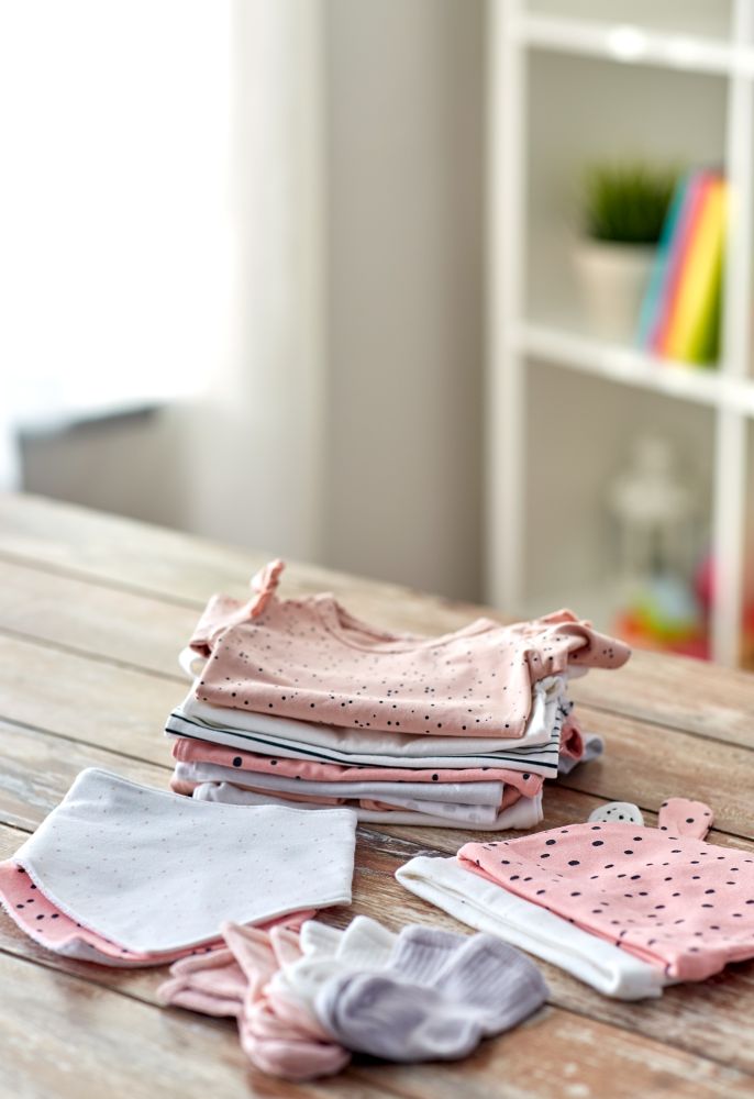babyhood and clothing concept - baby clothes on wooden table at home. baby clothes on wooden table at home