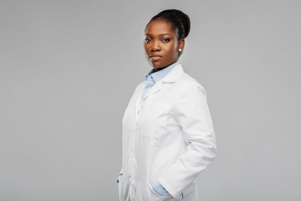 medicine, profession and healthcare concept - african american female doctor or scientist in white coat over grey background. african american female doctor or scientist