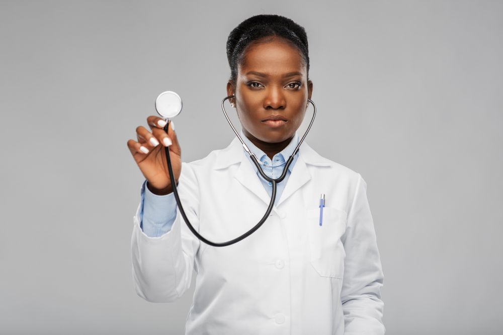 medicine, profession and healthcare concept - african american female doctor in white coat with stethoscope over background. african american female doctor with stethoscope