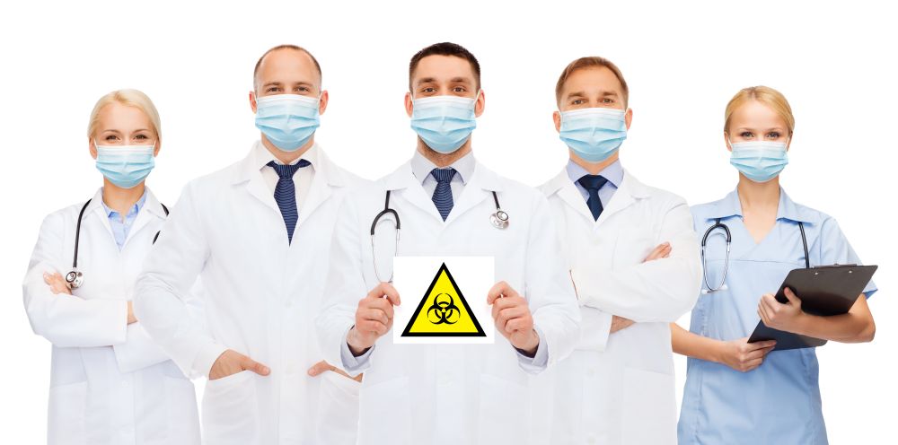 health, medicine and pandemic concept - doctors wearing protective medical masks holding biohazard caution sign on white background. doctors in medical masks with biohazard sign