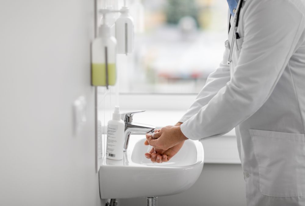 health care, hygiene and people concept - doctor washing hands at hospital sink. doctor washing hands at hospital sink
