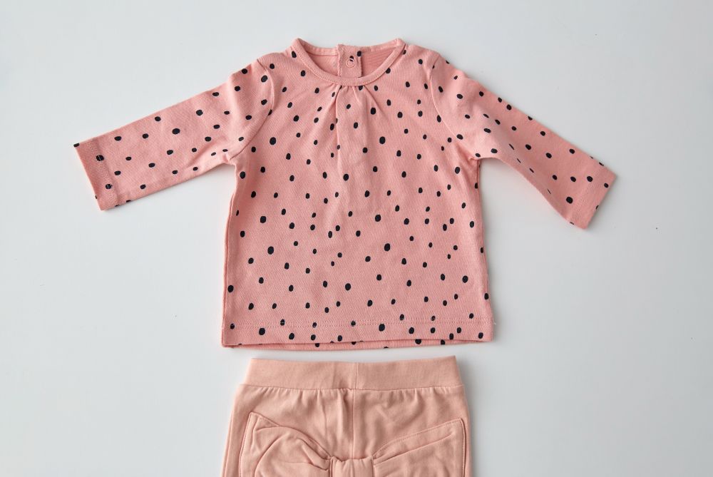 clothes, babyhood and clothing concept - pink long-sleeved shirt and pants for baby girl with dot print on white background. pink shirt and pants for baby girl over white