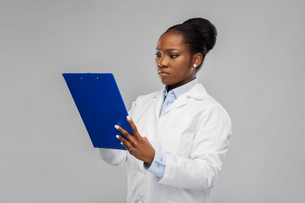 medicine, profession and healthcare concept - african american female doctor or scientist in white coat with clipboard over grey background. african american female doctor with clipboard