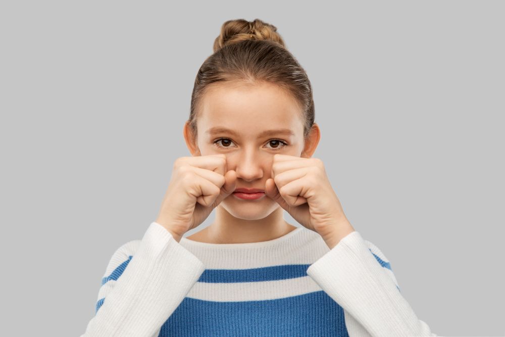 emotion, gesture and people concept - crying teenage girl in pullover over grey background. crying teenage girl in pullover