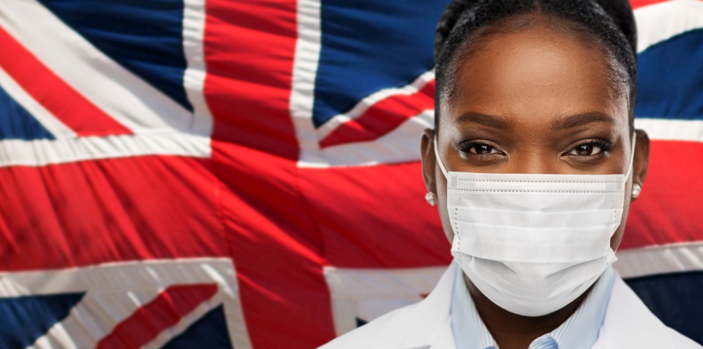 health, medicine and pandemic concept - close up of african american female doctor or scientist in protective medical mask over british flag background. african american doctor in medical mask
