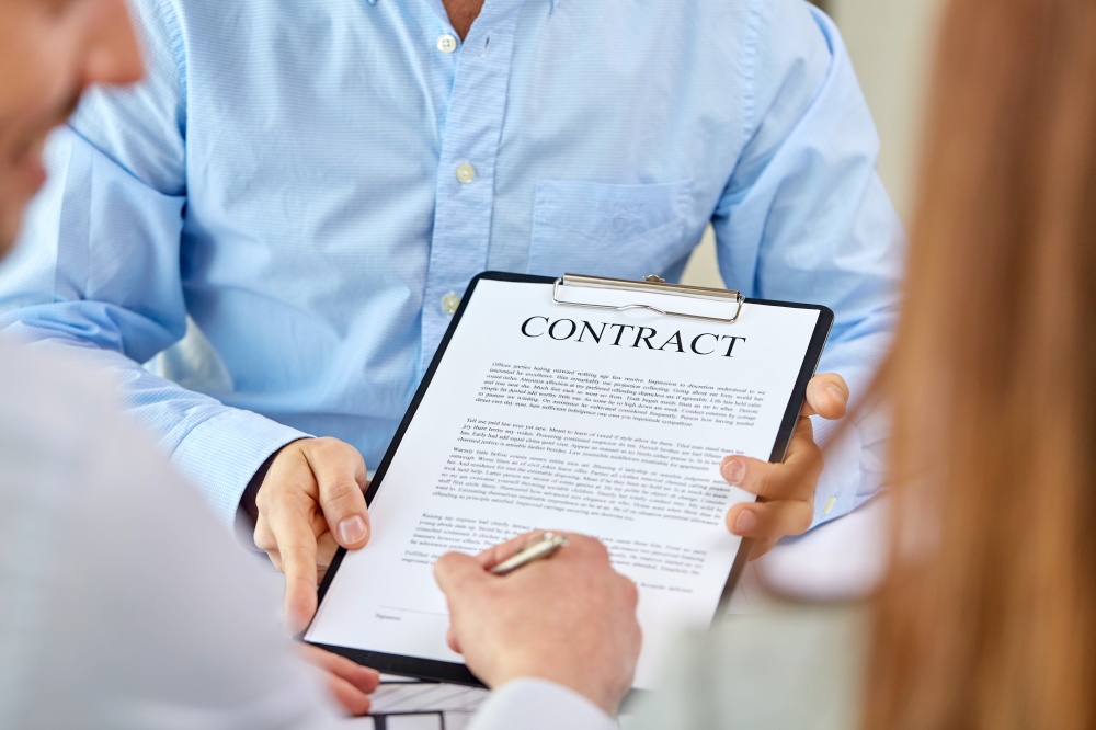 real estate business, sale and people concept - male realtor&rsquo;s hands and customers signing property purchase contract at office. customer signing contract document at office