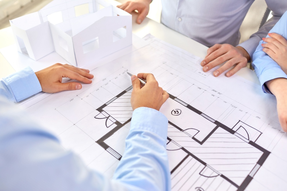 architecture, construction business and people concept - close up of architects discussing blueprint of house project at office. close up of architects with blueprint at office