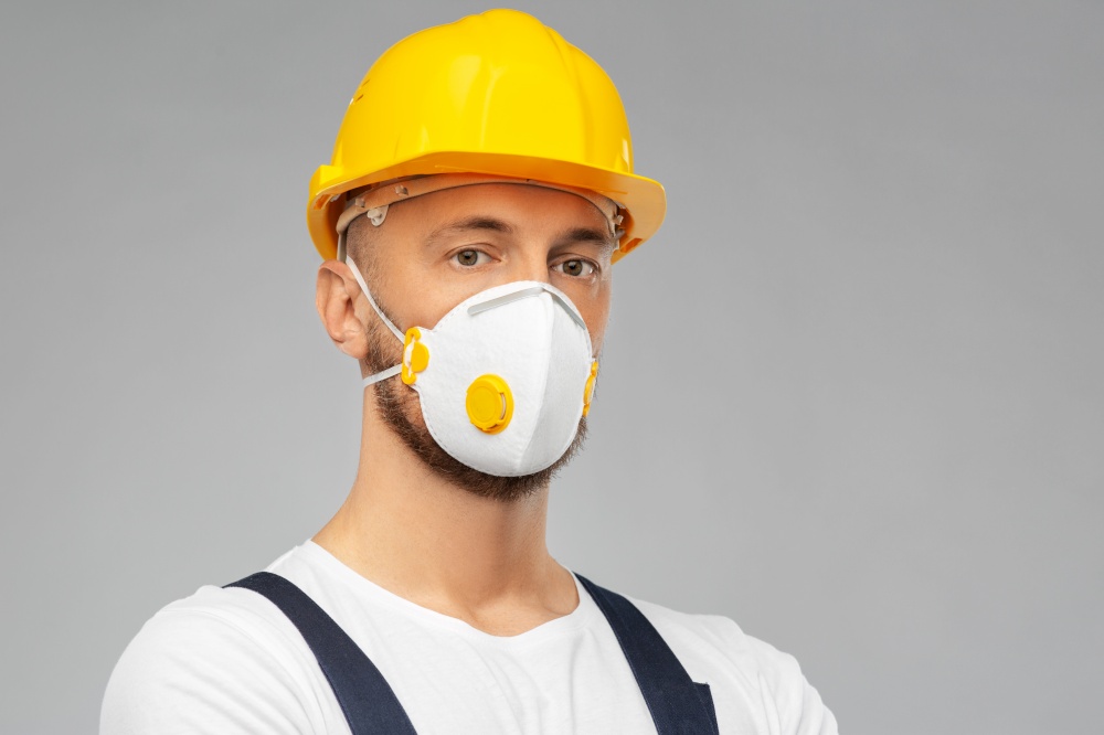 profession, construction and building - male worker or builder in helmet and respirator mask over grey background. male worker or builder in helmet and respirator