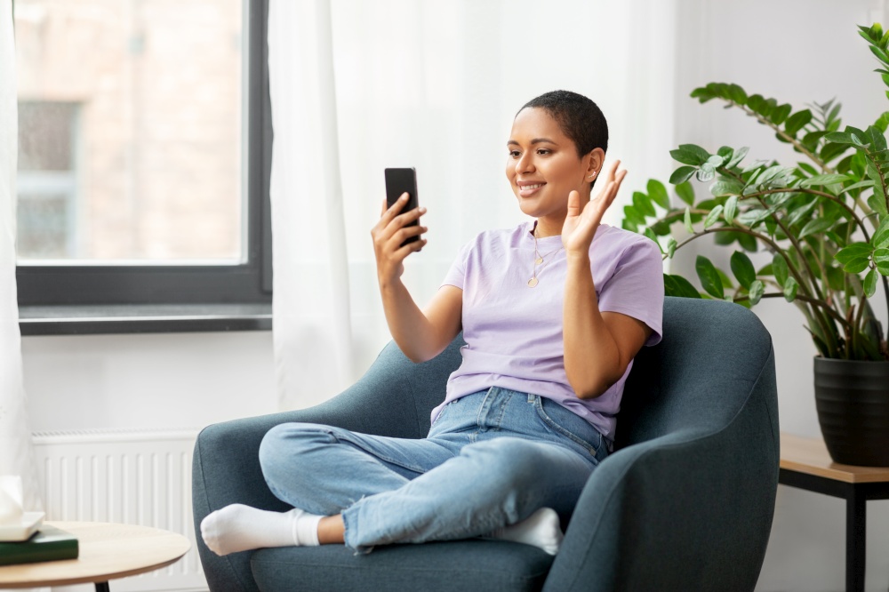 technology and people concept - smiling african american woman in glasses with smartphone having video call at home. woman with smartphone having video call at home