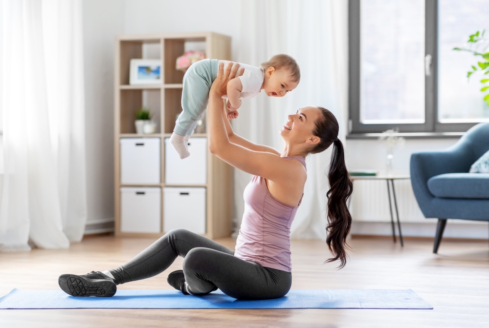family, sport and motherhood concept - happy smiling mother with little baby exercising at home. happy mother with little baby exercising at home