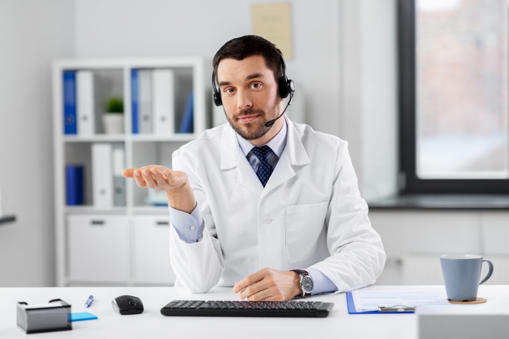 healthcare, medicine and technology concept - happy male doctor with headset having video call at hospital. male doctor in headset having video call at clinic