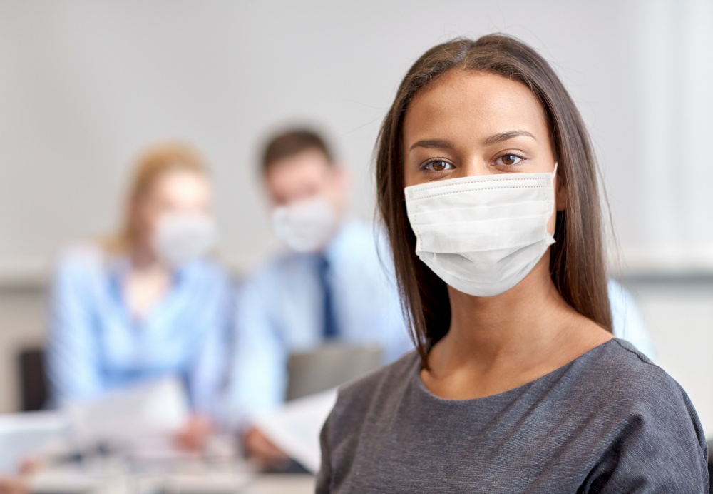 business, people and pandemic concept - african american businesswoman wearing face protective medical mask for protection from virus disease at office. african american businesswoman in mask at office