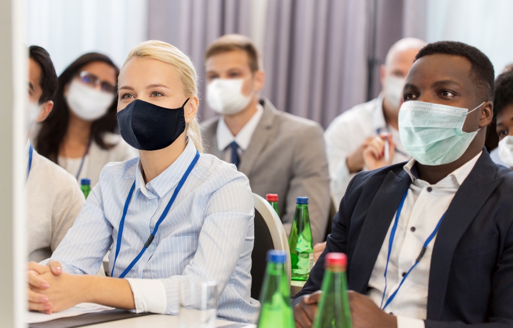 business and pandemic concept - group of people wearing face protective medical mask for protection from virus disease at international conference. business people in masks at worldwide conference