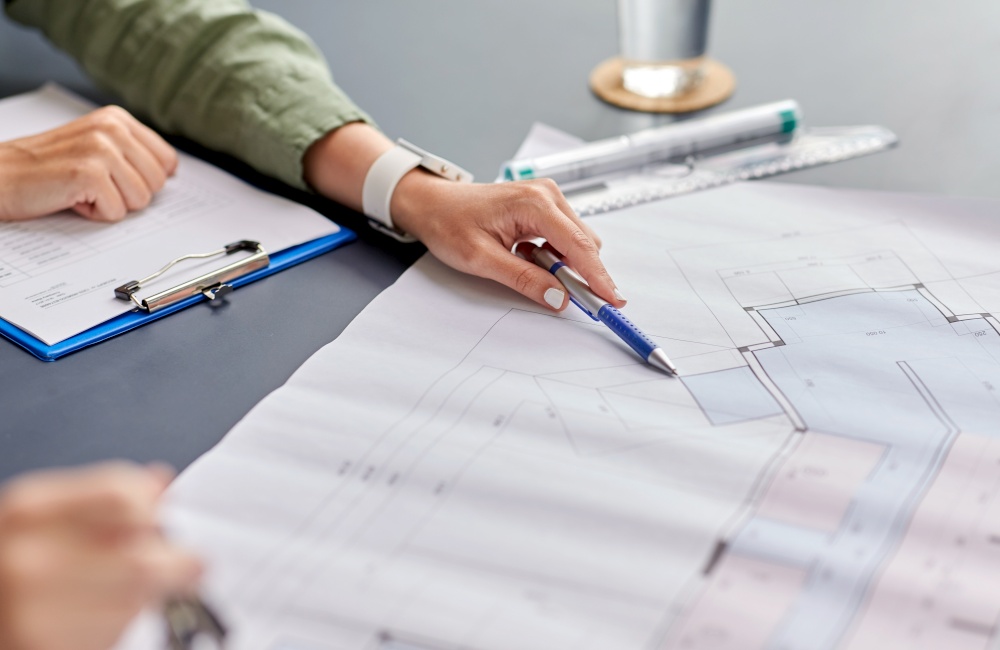 construction business, architecture and building concept - close up of architect with blueprint, clipboard and pen working at office. architect with blueprint working at office
