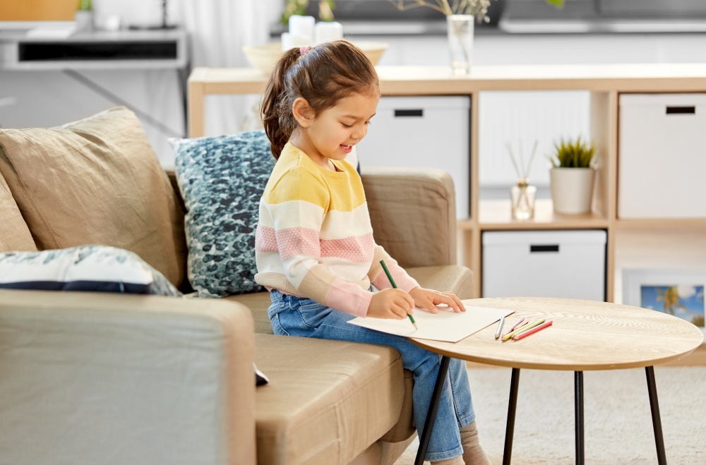 childhood, creativity and art concept - happy smiling little girl drawing with coloring pencils at home. little girl drawing with coloring pencils at home