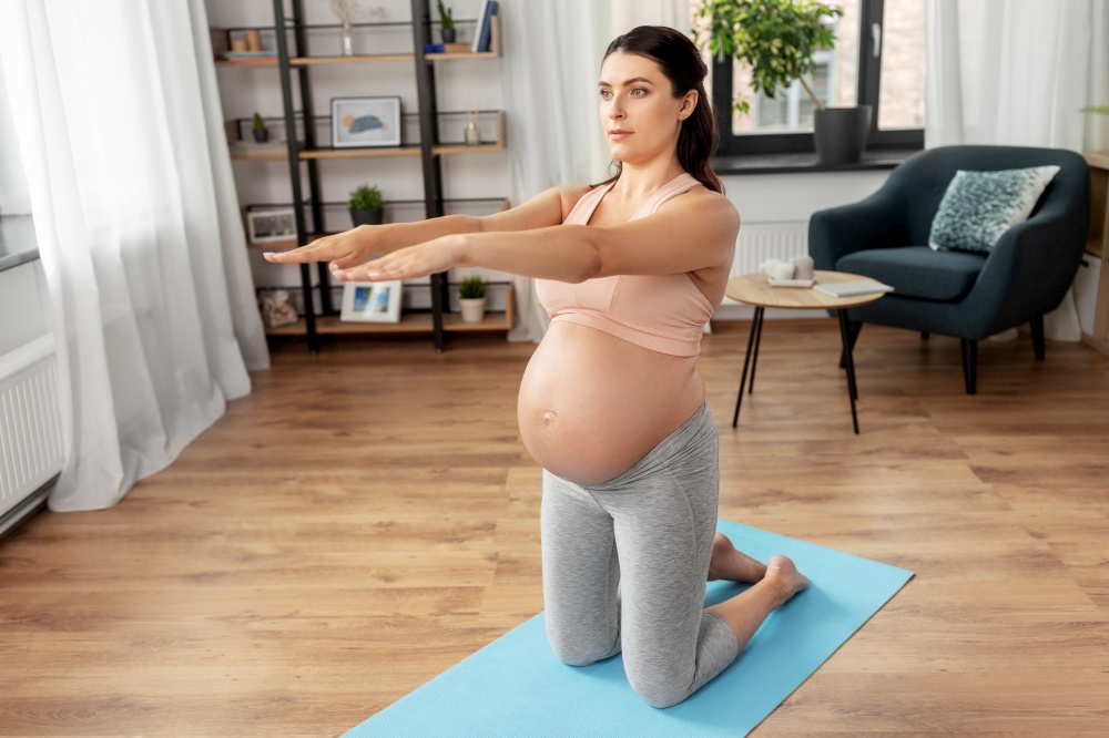 sport, fitness and pregnancy concept - happy pregnant woman exercising at home. happy pregnant woman doing sports at home