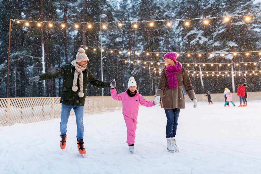christmas, family and leisure concept - happy mother, father and daughter at outdoor skating rink in winter. happy family at outdoor skating rink in winter