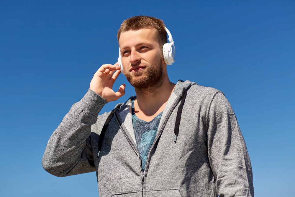 fitness, sport and lifestyle concept - young man in headphones listening to music outdoors. man in headphones listening to music outdoors