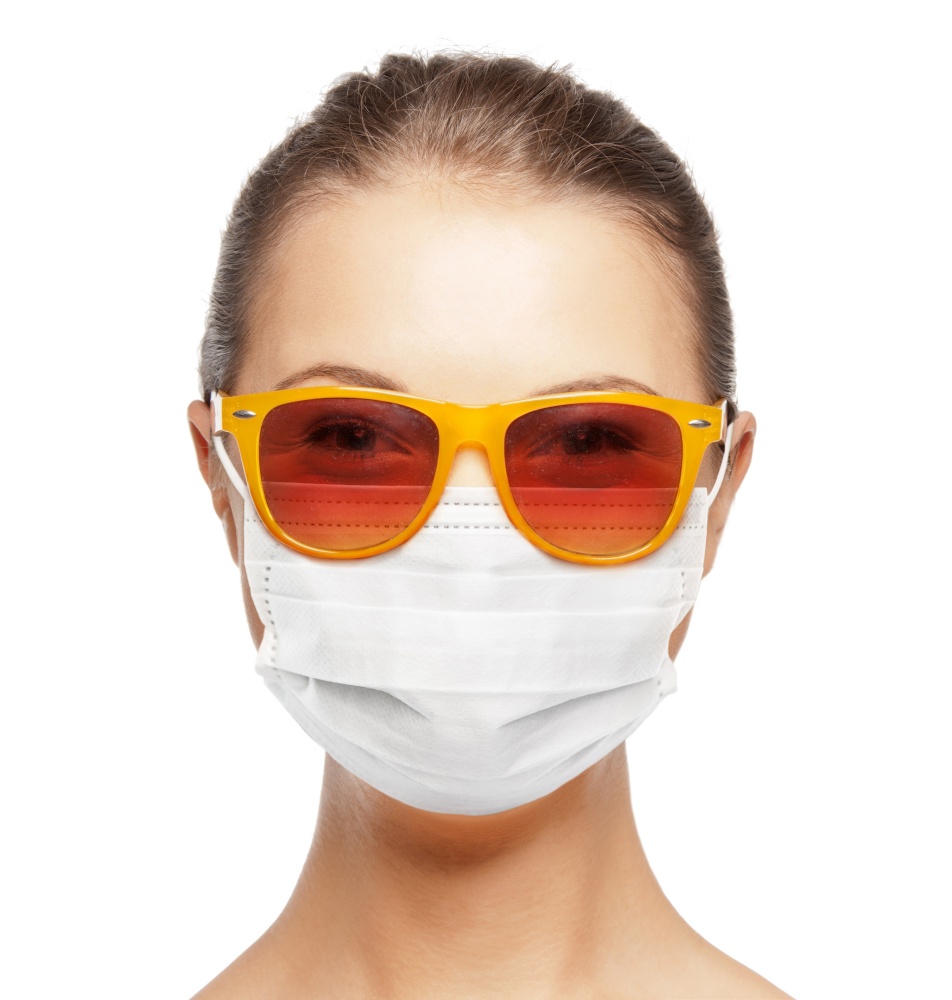 pandemic, health and people concept - portrait of teenage girl in sunglasses wearing medical face mask for protection from virus disease. teenage girl in medical mask and sunglasses