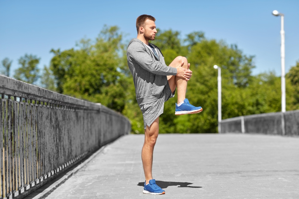 fitness, sport and healthy lifestyle concept - man stretching leg on bridge. man stretching leg on bridge