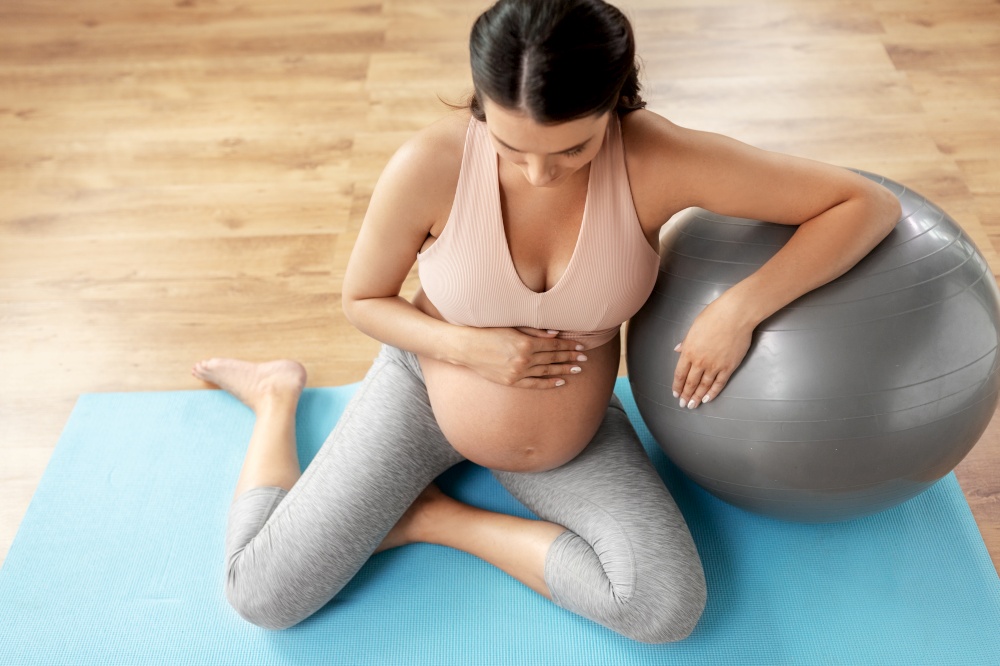 pregnancy, sport and fitness concept - happy pregnant woman exercising with fitball at home. happy pregnant woman with fitball at home
