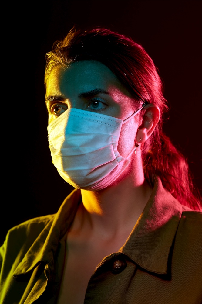 health, safety and pandemic concept - young woman wearing protective medical mask over black background. young woman wearing protective medical mask