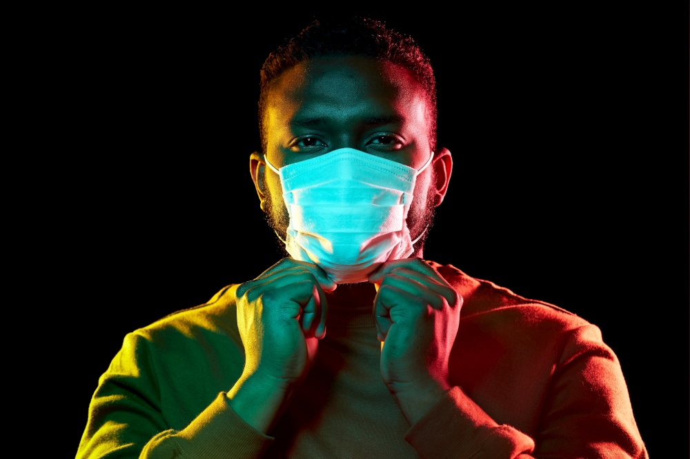 health, safety and pandemic concept - young african american man wearing protective medical mask over black background. african american man wearing medical mask