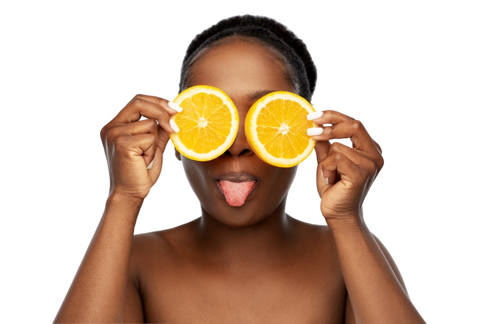 beauty, skin care and detox concept - beautiful african american woman making eye mask of oranges over white background. african woman making eye mask of oranges