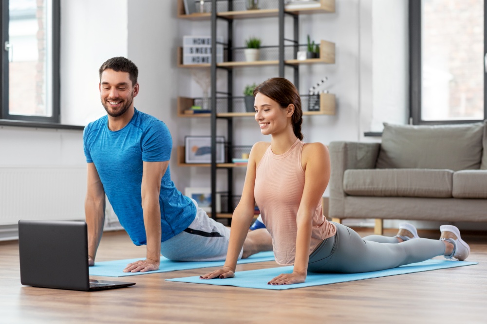sport, fitness, lifestyle and people concept - smiling man and woman with laptop computer exercising at home. happy couple with laptop exercising at home