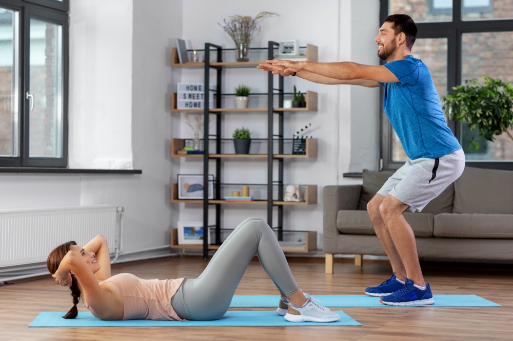 fitness, sport, training and healthy lifestyle concept - happy young man and woman exercising at home. happy young man and woman exercising at home