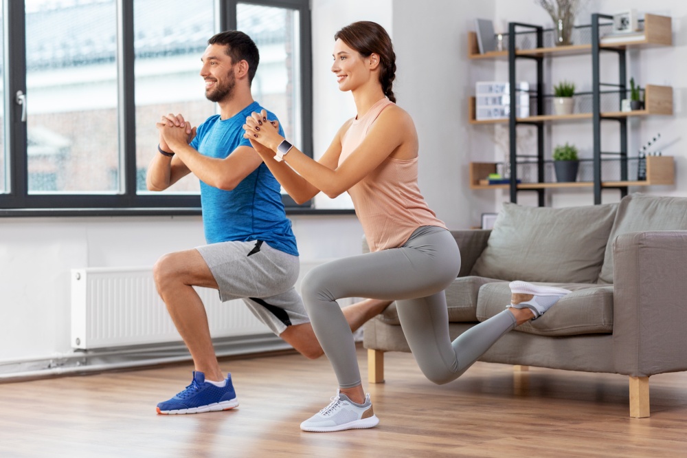 sport, fitness, lifestyle and people concept - smiling man and woman exercising and doing lunge using sofa at home. couple exercising and doing lunge at home