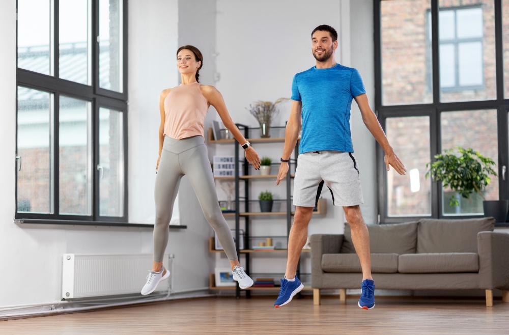 sport, fitness, lifestyle and people concept - smiling man and woman exercising at home. happy couple exercising at home
