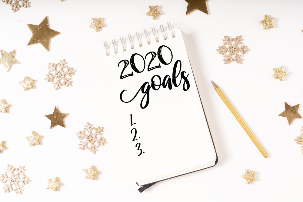 Wish list for Cristmas and 2020 New Year. Holiday decorations and ruled notebook with wish list on white desk, flat lay. Christmas flat lay scene with golden decorations