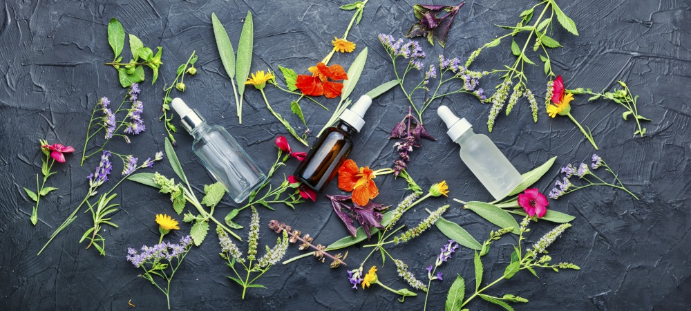 Essential oils of flowers and herbs.Natural medicine concept.Bottles of tincture and healthy herbs and flowers. Bottle with herb essential oil