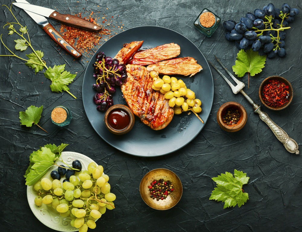 Roast chicken breast with grapes.Summer BBQ.Barbecued chicken meat.. Grilled chicken breast on concrete background